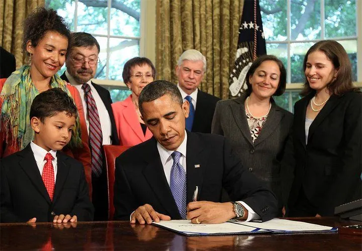 President Obama signs the Daniel Pearl Freedom of the Press Act, with the Pearl family looking on